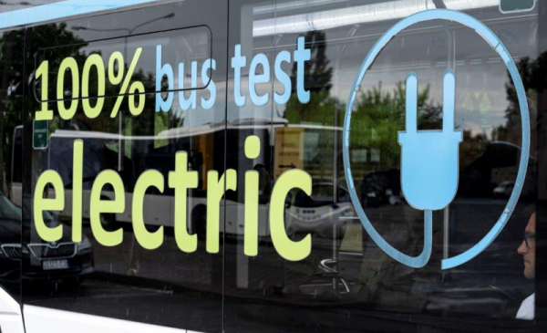 Na zdjęciu szyba autobusu elektrycznego z napisem "100 percent electric bus test"