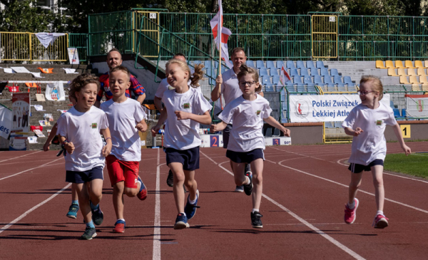 Na zdjęciu: dzieci biegną na bieżni na stadionie