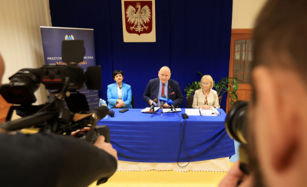 Na zdjęciu: konferencja prasowa, nad stołem wisi godło