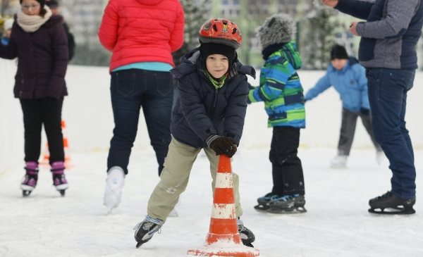 Na zdjęciu dzieci jeżdżą na łyżwach na lodowisku