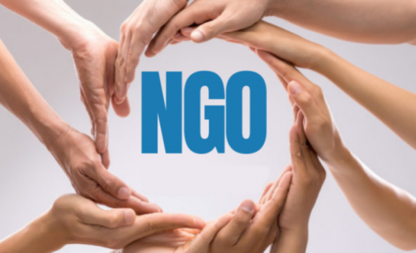 Niebieski napis NGO otoczony splecionymi dłońmi.