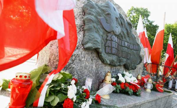 Kwiaty i flagi biało-czerwone pod obeliskiem Ku czci Żołnierzy Armii Krajowej na placu Rapackiego 