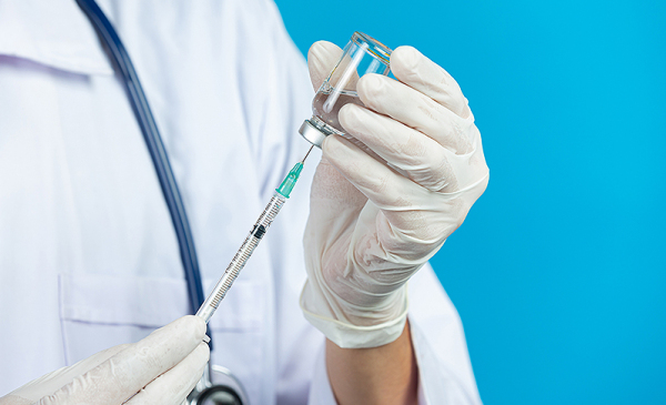 zdjęcie dłoni trzymających strzykawkę ze szczepionką