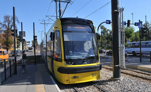 Zdjęcie przedstawia tramwaj w kolorach żółtym i niebieskim stojący na przystanku