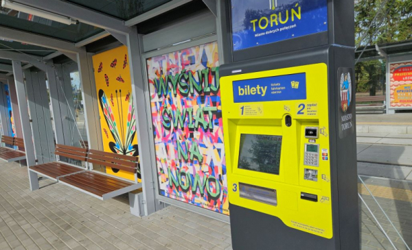Na zdjęciu: żółty biletomat zamontowany na przystanku komunikacji miejskiej