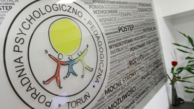 Na zdjęciu tablica z logo Poradni Psychologiczno-Pedagogicznej w Toruniu