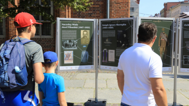 Mężczyzna i dwóch chłopców oglądają wystawę w Toruniu