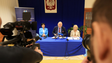 Na zdjęciu: konferencja prasowa, nad stołem wisi godło