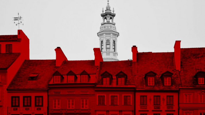 Zdjęcie wybarwionych na biało-czerwono kamienic i wieży