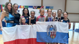 Na zdjęciu: grupa dziewcząt stoi na podium, trzymają biało-czerwoną flagę Polski i biało-niebieską z herbem Torunia