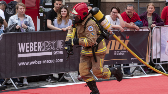 Na zdjęciu: strażak biegnie z wężem strażackim
