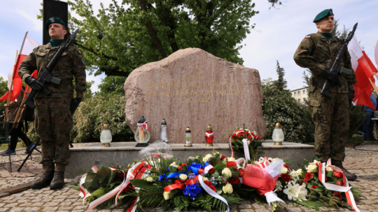 Na zdjęciu: pomnik pamięci ofiar hitleryzmu, przed nim leżą wiązanki kwiatów, obok warta honorowa