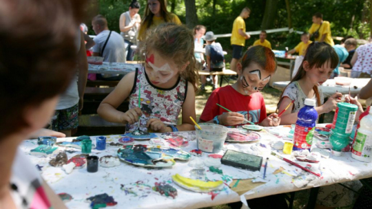 Na zdjęciu: podczas pikniku dzieci malują farbami, w tle drzewa