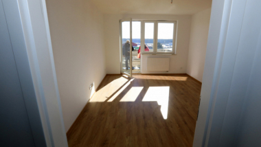 Na zdjęciu: pusty pokój, widać okno i drzwi balkonowe, przez które wpadają promienie słońca