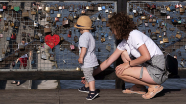 Na zdjęciu: kobieta i dziecko oglądają kłódki przytwierdzone do balustrady tarasu widokowego