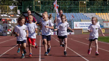 Na zdjęciu: dzieci biegną na bieżni na stadionie