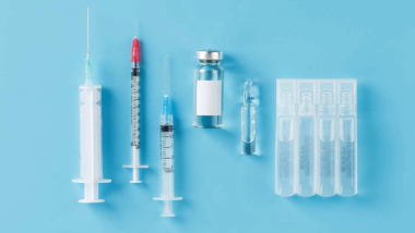 Na zdjęciu strzykawki z ampułkami ze szczepionką na niebieskim tle