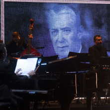 Muzycy na scenie, w tle zdjęcie Wojciecha Młynarskiego