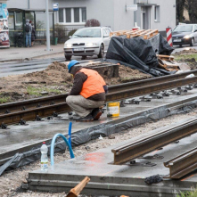 Robotnik prowadzi prace związane z ukladaniem torów tramwajowych