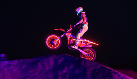 Na zdjęciu widać podświetlonego zawodnika wykonującgo motocrossowe ewolucje