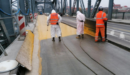 Pracownicy zajmują się robotami związanymi kładzeniem nawierzchni na moście