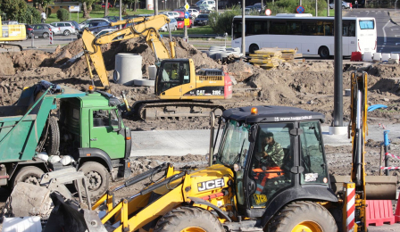 Żółta koparka, zielona ciężarówka i inne sprzęty budowlane wśród wykopów na placu Niepodległości